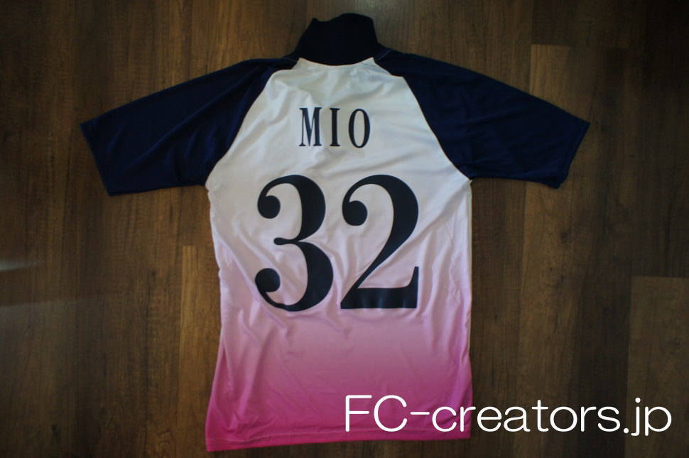 白地にピンクのグラデーションを昇華プリントしたサッカーユニフォームの選手名と背番号