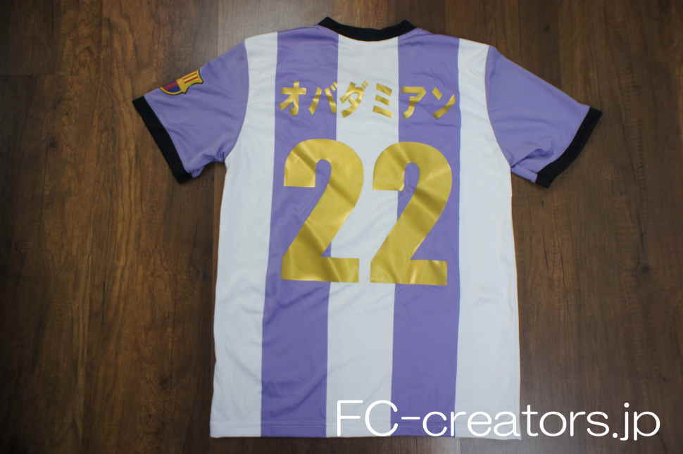 白と紫のストライプ柄のサッカーシャツに金色の背番号をプリント