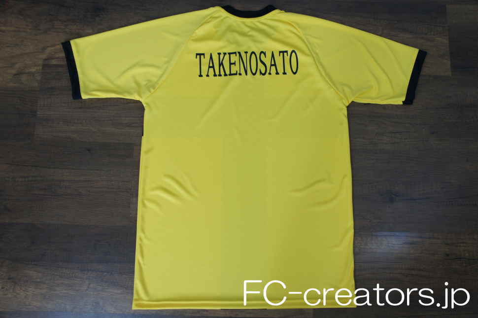 黄色に黒地の十字柄を昇華プリントしたサッカー部のユニフォームに黒地のチーム名を印刷
