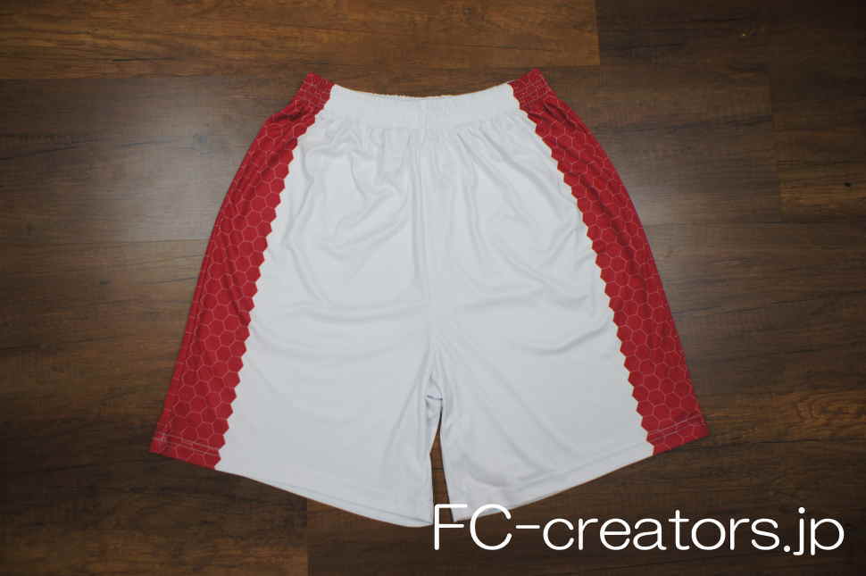 白地に赤のハニカム模様を左右にプリントしたサッカーパンツの表