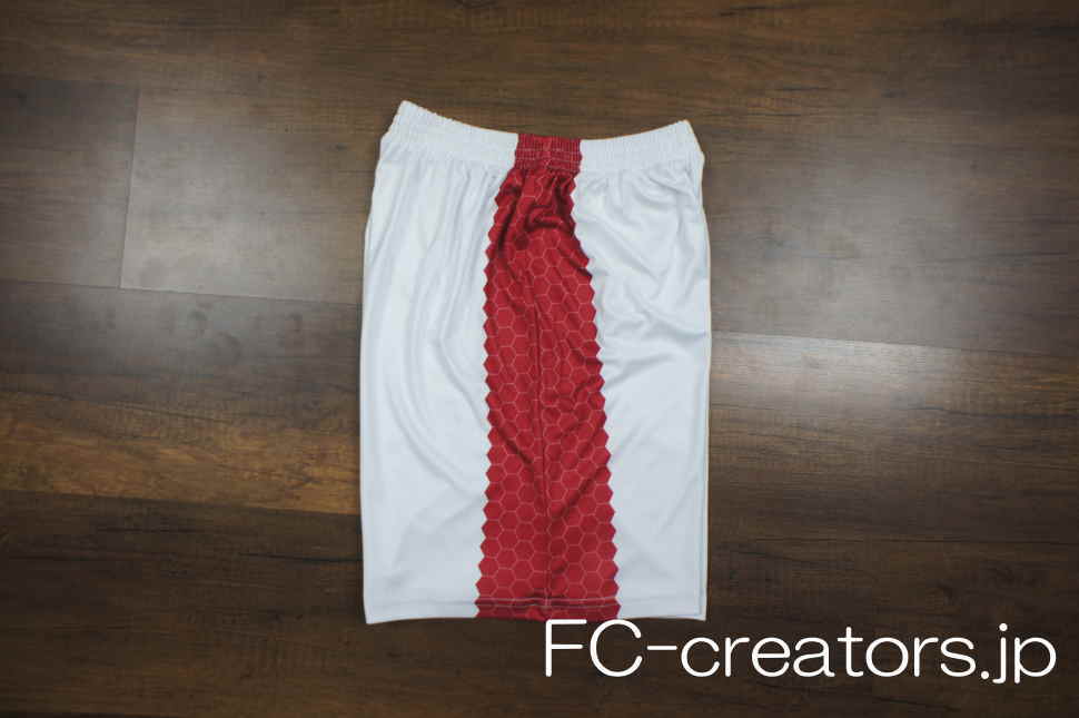 白色のサッカーパンツの左右両側に赤色のハニカム模様をプリント